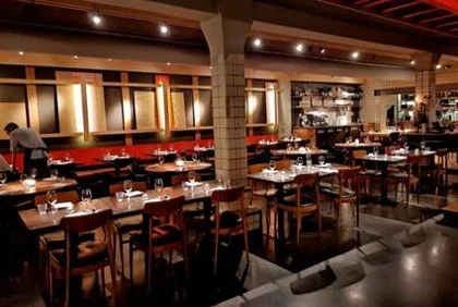 Modern ingerichte eetzaal van een restaurant aan de De Ruijterkade, met keurig gedekte tafels en sfeervolle verlichting.